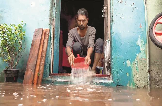 A man draining water from his house in Baroda