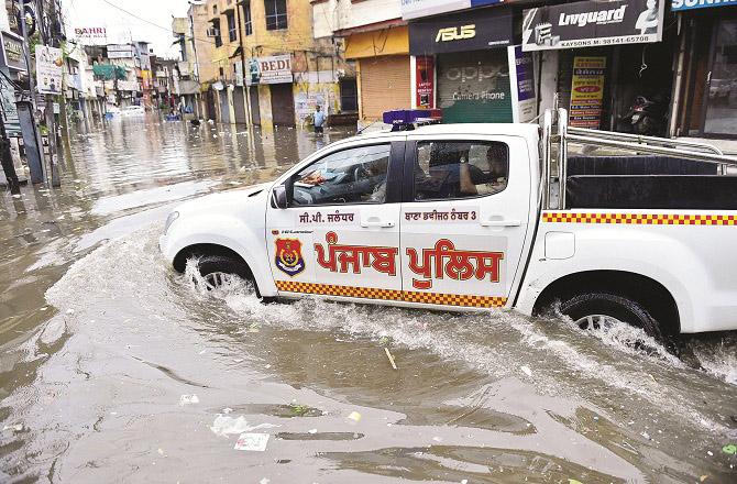 A car passes through a flooded area in Jalandhar. Photo: PTI