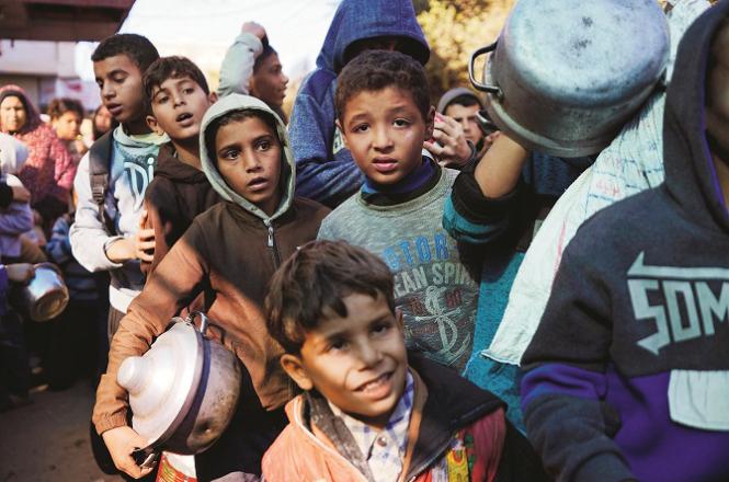 Hungry children line up outside a food distribution center to receive food. Photo: INN