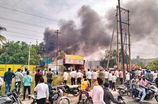 Smoke billowing from the Tirumala Oil Mill and crowds can be seen