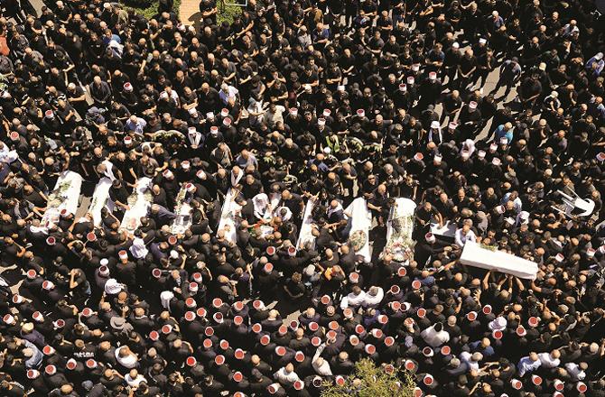 Mourners gather around the bodies of those killed in the attack on the Golan Heights. Photo: PTI.