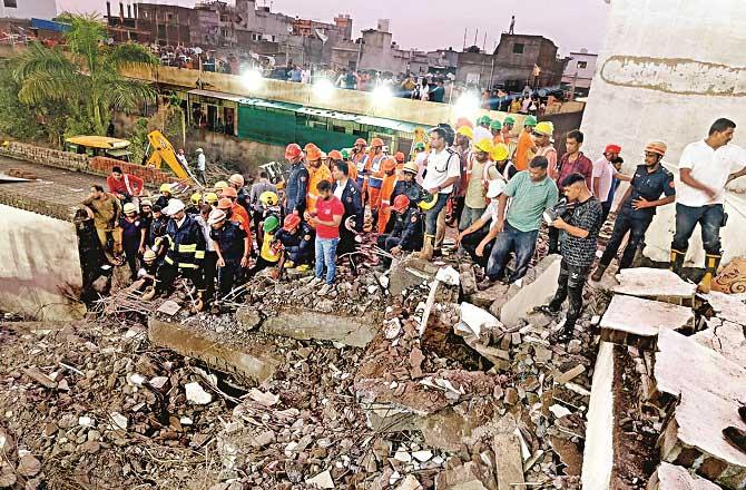 Rescue workers and local people on the rubble of the building. Photo: PTI