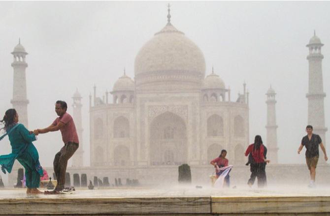 In the Taj Mahal premises, people were drenched in rain. Photo: PTI.