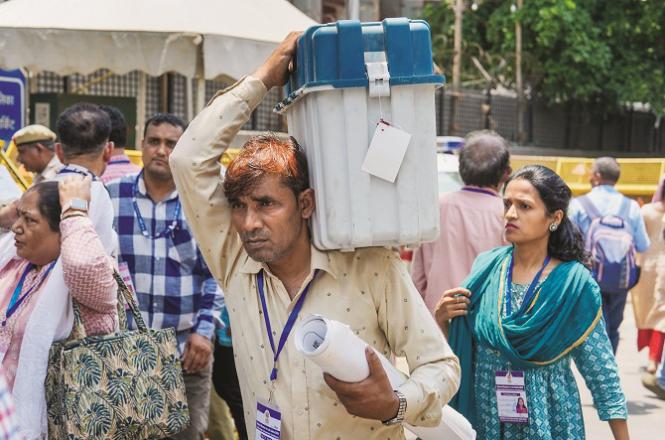 A polling volunteer carries a machine in Delhi. Photo: PTI