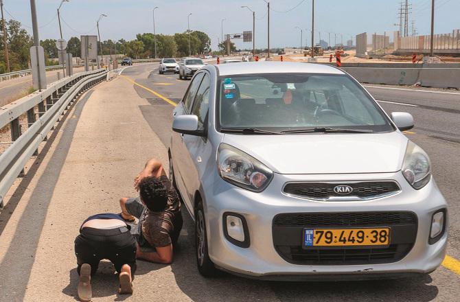 Civilians can be seen lying on the ground on Tel Aviv`s highway after the sirens of rocket attacks. Photo: Agency