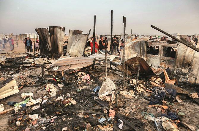 People are looking at the destroyed tents as a result of Israeli bombing in Rafah. Photo: AP/PTI